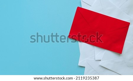 A stack of white envelopes with a red envelope on top. Blue background with copy space.