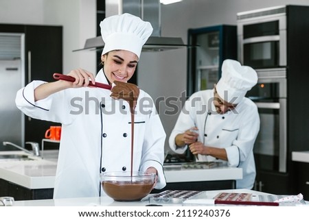 latin woman pastry chef wearing uniform holding a bowl preparing delicious sweets chocolates at kitchen in Mexico Latin America Royalty-Free Stock Photo #2119240376