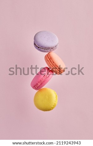 Colorful delicious French dessert macaron or macaroons flying or falling in motion on pink background. Royalty-Free Stock Photo #2119243943