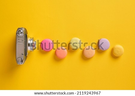 Color theory and photography concept. Colorful macarons designed as light waves with a vintage camera. 