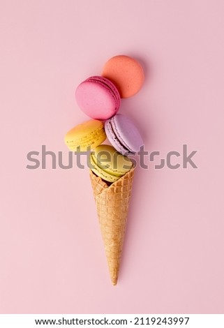 Colorful delicious macaron or macaroons in an ice cream waffle cone. Summer dessert concept.