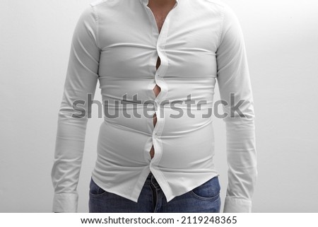Man wearing tight shirt on white background, closeup. Overweight problem Royalty-Free Stock Photo #2119248365
