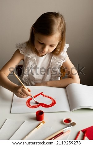 Girl painting red heart card for valentines day on white table, crafting, top view, copy space, love, Valentines day and mothers day concept, lifestyle