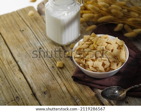 Cereal crunchy snacks in a bowl, milk and cereals - a quick breakfast on a wooden background. Country style. Children's and school food, sports, diet food. Healthy lifestyle. Advertising, banner.