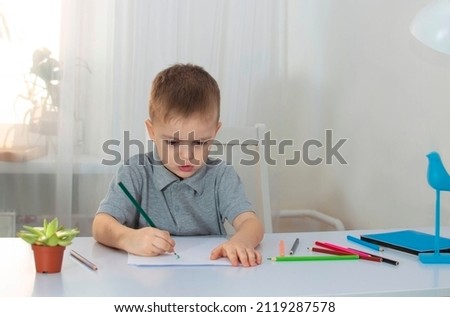 The boy draws in his room at his desk. The child is engaged in creativity at home. The concept of children's creativity. Selective focus.