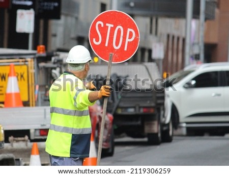 Older man with a stop sign directing traffic in Sydney cbd