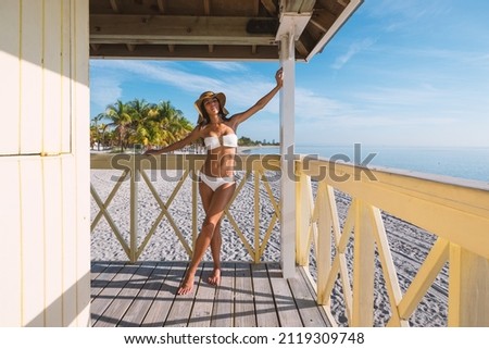 Beautiful woman wearing swimsuit relaxing on a Lifeguard tower in the beach of Crandon Park in a sunny day. Key Biscayne. Miami, florida.