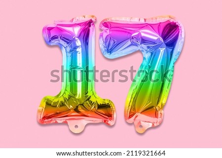 Rainbow foil balloon number, digit seventeen on a pink background. Birthday greeting card with inscription 17. Top view. Numerical digit. Celebration event, template. Royalty-Free Stock Photo #2119321664