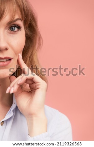 Portrait of a happy smiling mature woman with hand on chin looking at camera. Close up face of beautiful woman with fair hair on rose background. Copy spase for text