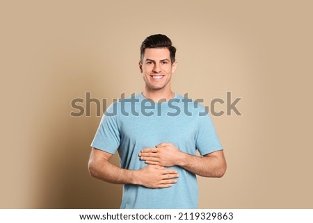 Happy healthy man touching his belly on beige background Royalty-Free Stock Photo #2119329863