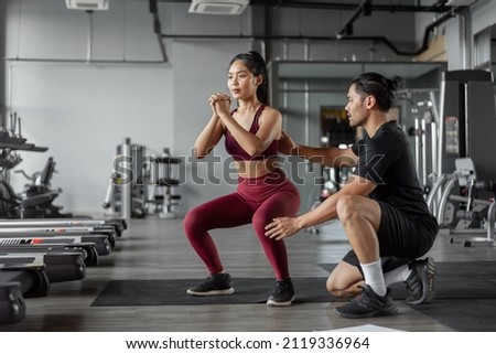 Asian woman exercise with personal trainer in gym. Young healthy woman workout in fitnees with personal coach. Exercises and fitness concept. Royalty-Free Stock Photo #2119336964
