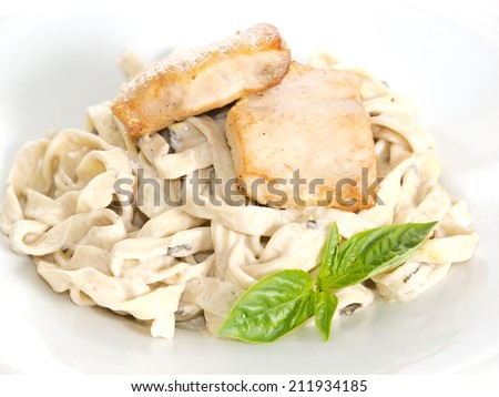 fettuccine with sauce bechamel and fried fish fillet on white background