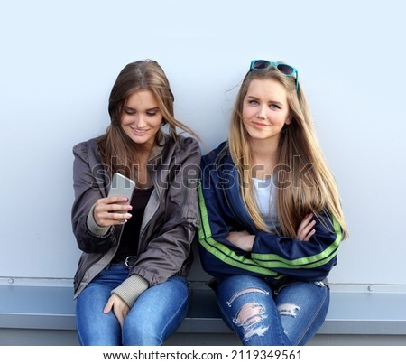 two girls walking the streets, laughing ,taking pictures ,using smartphone