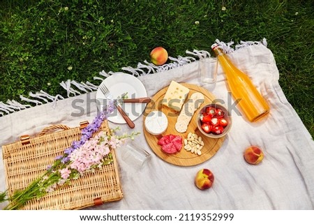 leisure and drinks concept - close up of food, drinks and basket on picnic blanket on grass Royalty-Free Stock Photo #2119352999