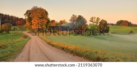 An old country asphalt road through the village, green hills, trees and fields. Traditional house close-up. Russia. Autumn rural scene. Architecture, agriculture, farm, ecology. countryside, tourism Royalty-Free Stock Photo #2119363070