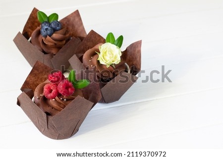 Cupcakes  decorated with raspberry and blueberries , fresh rose flower. Cup cakes background, baking design background