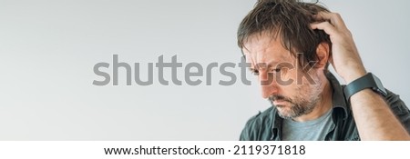 Forgetfulness concept, guy scratching his head trying to remember something, panoramic image with copy space Royalty-Free Stock Photo #2119371818