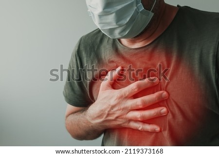 Covid-19 chest pain as infection symptom, man with respiratory mask holding a hand at his chest Royalty-Free Stock Photo #2119373168