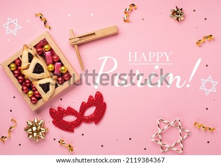 Purim celebration jewish carnival holiday card. Homemade hamantaschen cookies, red carnival mask, noisemaker, sweet candies and party decor on pink background. Top view, flat lay. Happy Purim concept.