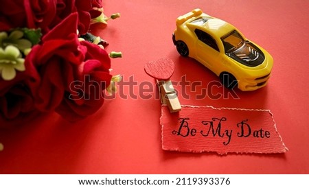 Be my date text on torn red paper with roses and yellow toy car background. Happy Valentine's day concept.