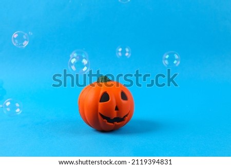 Halloween pumpkin jack with soaring soap bubbles on blue background. Halloween minimal layout