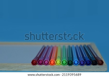 Selective Focus of A Set of Colourful Magic Pens On A Wooden White Board Isolated with Blue Background 