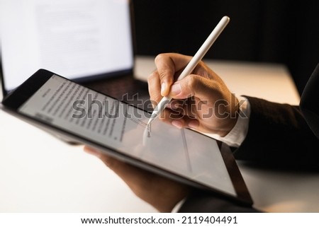 Close up businessman hand electronic Signature on Tablet by Stylus. Write business agreement of contract. Man signing contract on tablet. Business and technology concept. Royalty-Free Stock Photo #2119404491
