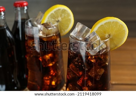 Glasses of refreshing soda water with ice and lemon slices on blurred background, closeup