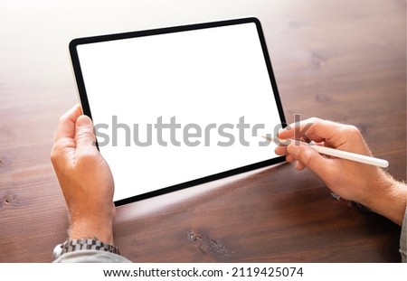 Person working on tablet computer with stylus pen, blank screen mockup