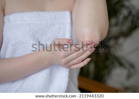 Young girl applying cream on the body in the bathroom