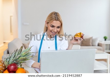 Doctor nutritionist writing case history in the office. Young woman dietitian prescribing recipe. Female nutritionist sitting at table with clipboard and healthy products on white background