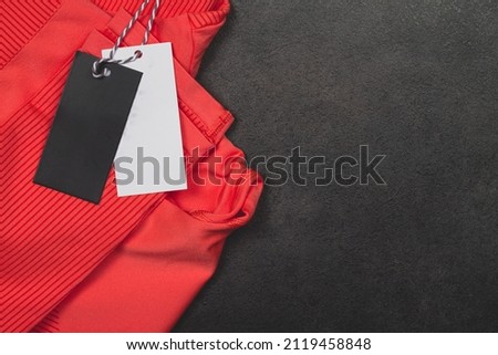 Black and white labels on a red sports suit on a black background. Copy Space