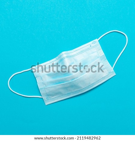 Surgical mask on a blue background. A typical three-layer surgical mask to cover the mouth and nose. Bacteria mask procedure. Protection concept