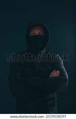 Scary man hiding in the shadows, with the face and identity hidden with the hood. Concept for fear, mystery, danger, crime, stalker