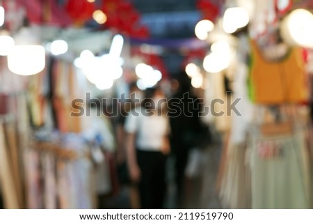 Defocused outdoor flea market at night with people and lights in background. Picture was blurred in purpose.