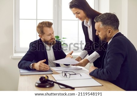 Group of experienced attorneys and lawyers giving consultation to client, helping with difficult lawsuit, explaining legal procedures and discussing agreement terms. Law services and support concept Royalty-Free Stock Photo #2119548191