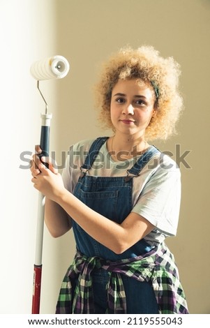 Yound beautiful caucasian woman smiling to the camera posing with paint roller - copy space. High quality photo