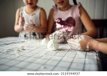 Funny children play with artificial snow at home in the kitchen. Educational classes and experiments with children at home. Sensory development and games at home. Snow from starch and shaving foam