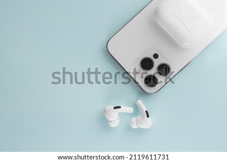 white phone with white wireless headphones on a blue background Royalty-Free Stock Photo #2119611731
