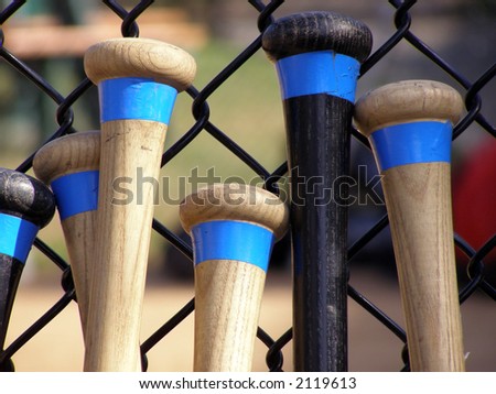 Baseball bats leaning against a batting cage fence. Royalty-Free Stock Photo #2119613