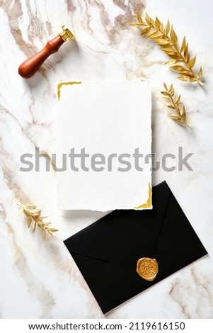Luxury wedding invitation card mockup with black envelope and wax seal stamp on gold marble table..Wedding stationery set top view.