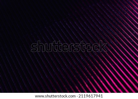Ridged texture. Blur glow overlay. Fluorescent light reflection. Neon pink purple color gradient radiance on dark black grooved surface abstract background.
