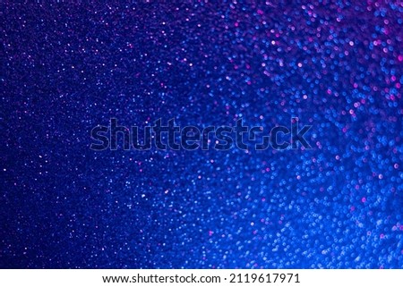 Neon glitter background. Bokeh glow. Defocused sparkles. Blur fluorescent light blue pink color grain texture shimmering round sequin pattern. Royalty-Free Stock Photo #2119617971