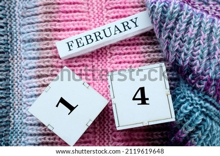 Calendar for February 14: cubes with the numbers 14, the name of the month of February in English on multi-colored jersey, top view