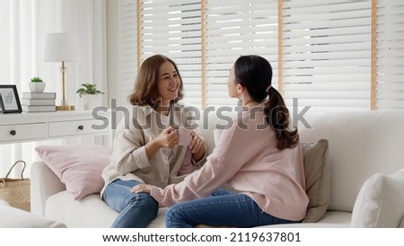 Young senior citizen authentic real family sit talk to grown up children kid with love share moment at home living room feeling positive relax enjoy listen to child girl. Parent coach communication. Royalty-Free Stock Photo #2119637801