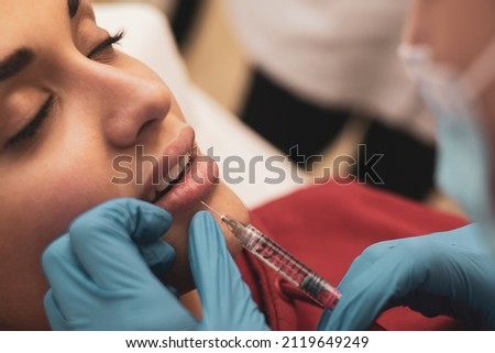 Cosmetologist makes injections in the lips and face of a beautiful woman in a beauty salon. Female cosmetology in the beauty salon.