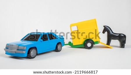 Trailer with a box for transporting horses. Plastic toy multicolored cars isolated on white background.
