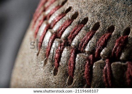 Close macro photograph of the laces on a baseball. The dramatic lighting shows intense texture and detail.