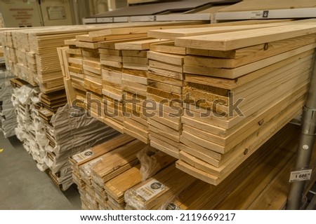 A stack of boards in a hardware store. Wooden products for construction and repair. Assortment of wooden sticks. Construction materials in warehouse. Selective focus