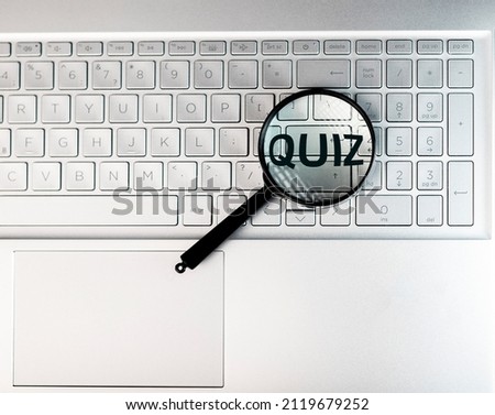 Quiz word through magnifying lens on laptops keyboard.